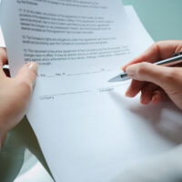 female hands filling out employment agreement contract